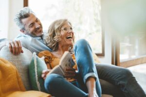 Cheerful mature couple sitting on sofa at home