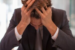 Frustrated businessman sitting at desk with  head in hands