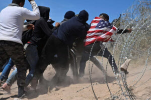 Migrants try to cross concertina wire at the U.S.-Mexico border near El Paso