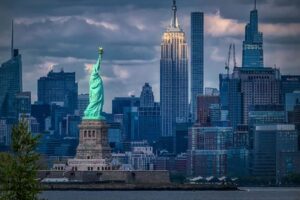 View of the Statue of Liberty and the Empire State Building with the late afternoon light shining down.