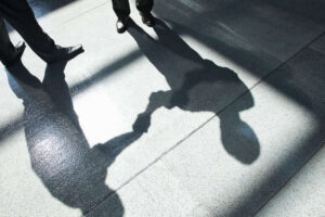 A shadow on a tiled floor of two businessmen shaking hands.