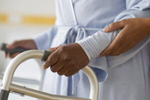 Nurse helping woman use walker in hospital hallway