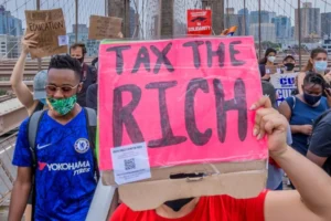 a-person-holds-a-tax-the-rich-sign-at-a-june-27-2020-protest-march-on-the-brooklyn-bridge-in-new-york-city