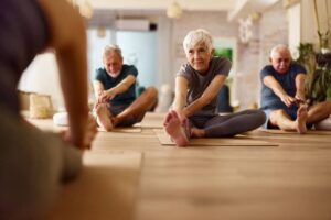 Active seniors stretching on exercise class in a health club.