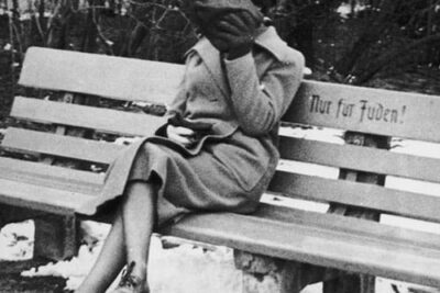 A-Jewish-woman-who-is-concealing-her-face-sits-on-a-park-bench-marked-Only-for-Jews-Austria-1938small