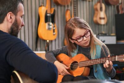 Dad,Teaching,Guitar,And,Ukulele,To,His,Daughter.little,Girl,Learning