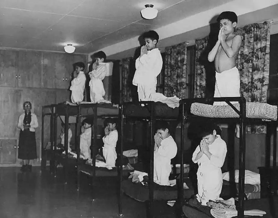 Indigenous children forced to pray to god in a residential school ran by the Canadian government and Catholic Church between 1930 and 1970, unknown location